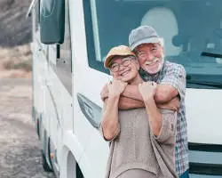 Happy elderly couple hugging by their motorhome.